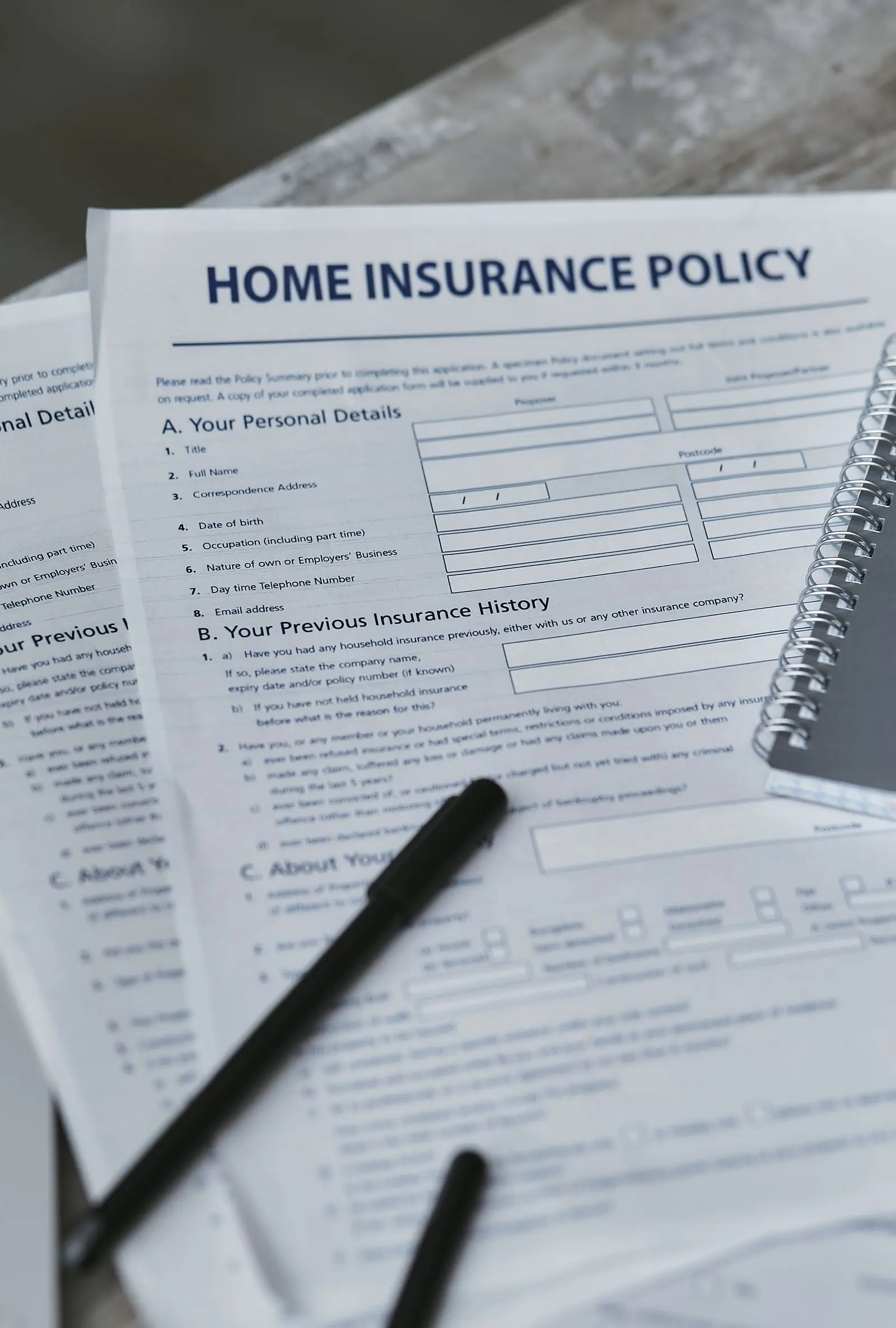 An insurance policy form and a notebook on a desk, seen from above