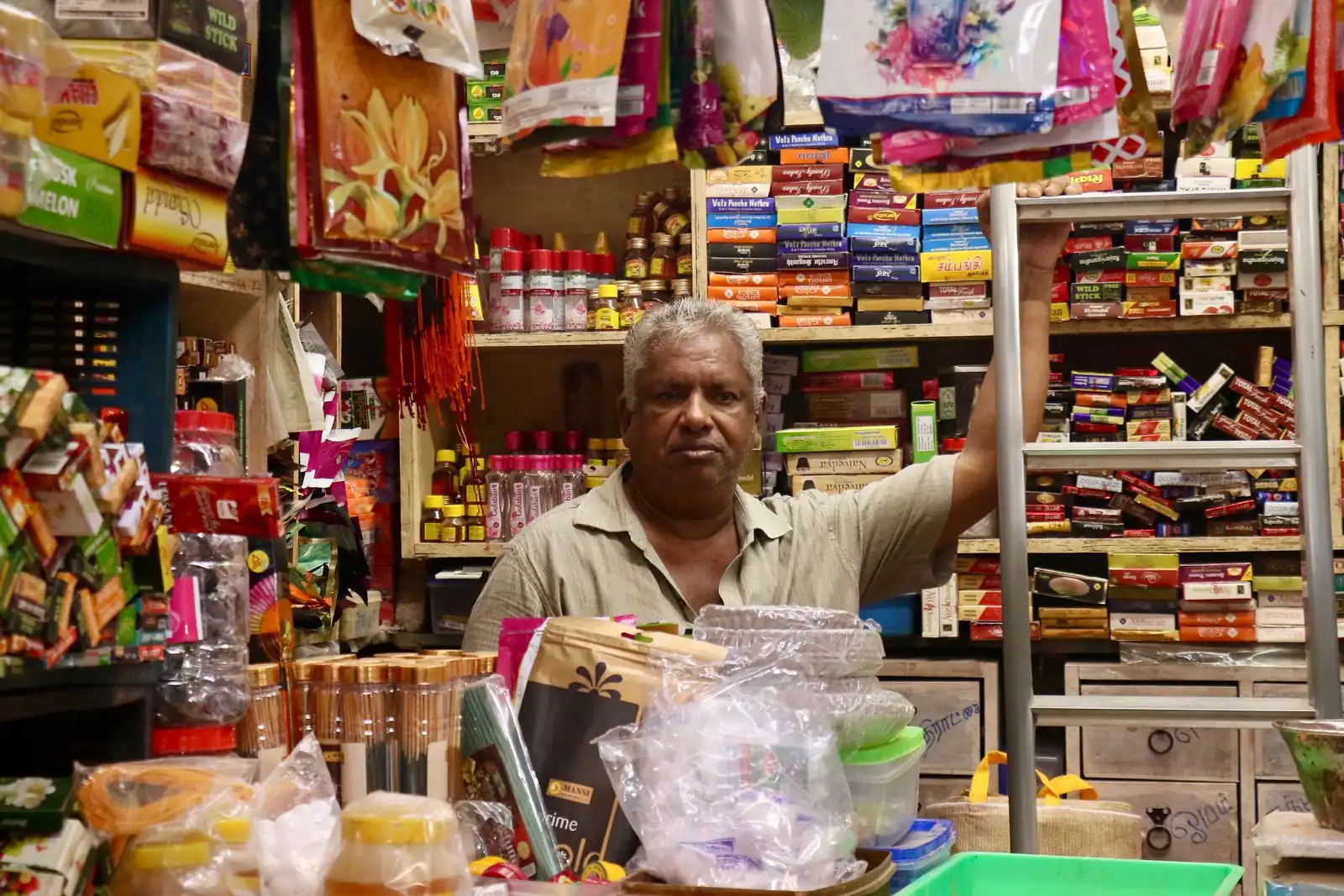 Shop owner behind the counter of a small Indian store